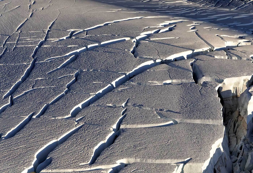 Aerial view of wind affected snow and ice with dramatic shadows cast by sun and cloud